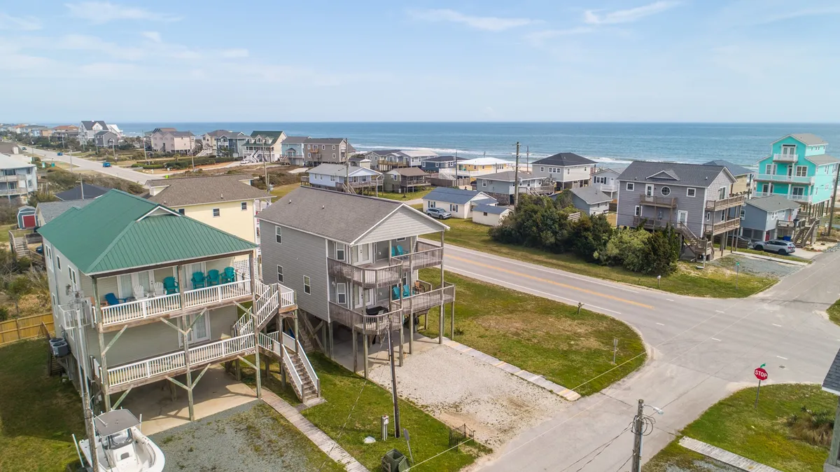 A scenic view showing beach houses with the ocean just beyond, and a small road leading directly to the sand. The tranquil scene captures the proximity to the beach and the inviting atmosphere of North Topsail Beach.