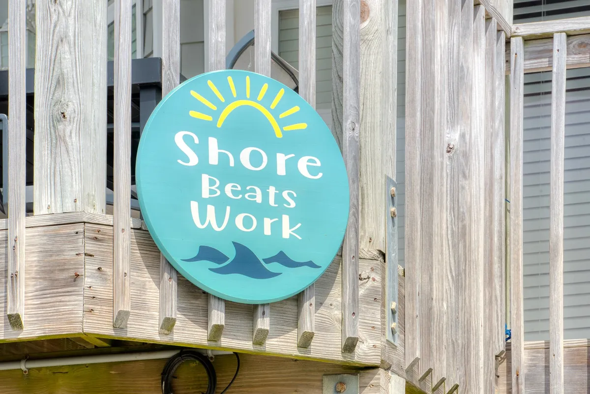 The exterior scene features cheerful signage, a wooden railing, and balcony space. The casual and social atmosphere suggests a place where guests and their dogs can gather, enjoy the outdoors, or simply watch the world go by.