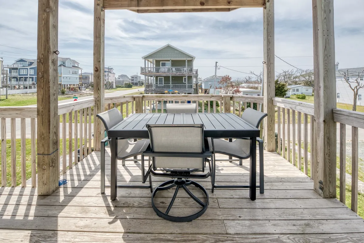 A welcoming outdoor dining table set in a green yard, surrounded by neighboring homes, perfect for al fresco meals, sunset dinners, or casual barbecues.