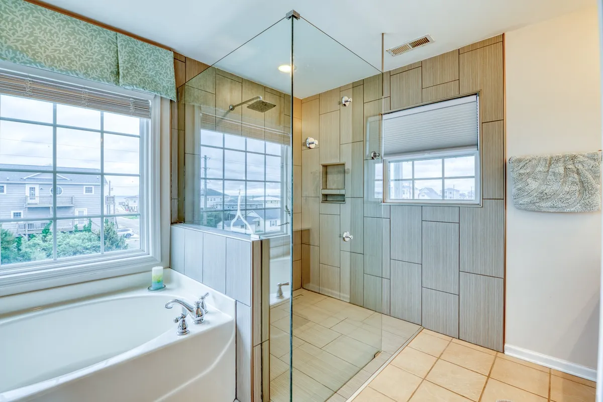 A luxurious spa-style bathroom with a deep soaking tub, spacious shower area, and a large window offering a scenic view. The atmosphere is calm and rejuvenating, perfect for unwinding in privacy.
