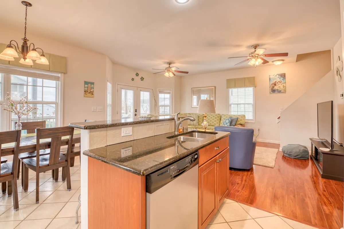 An inviting open-concept living area featuring a kitchen island, dining table, large living room couch, and a television. The space is designed for family meals, movie nights, and social gatherings.